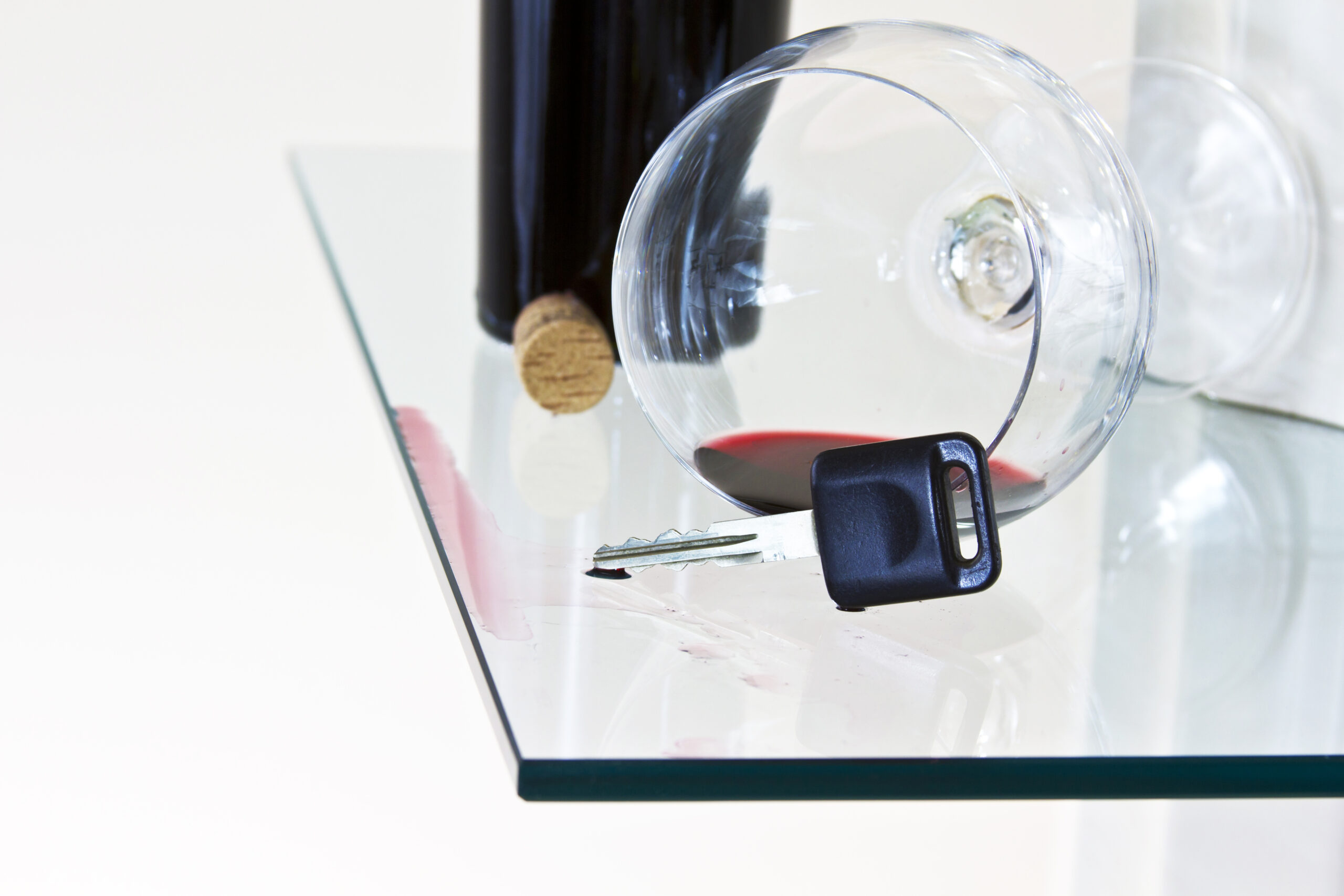 Spilled wine with car key and bottle of wine on glass bar top