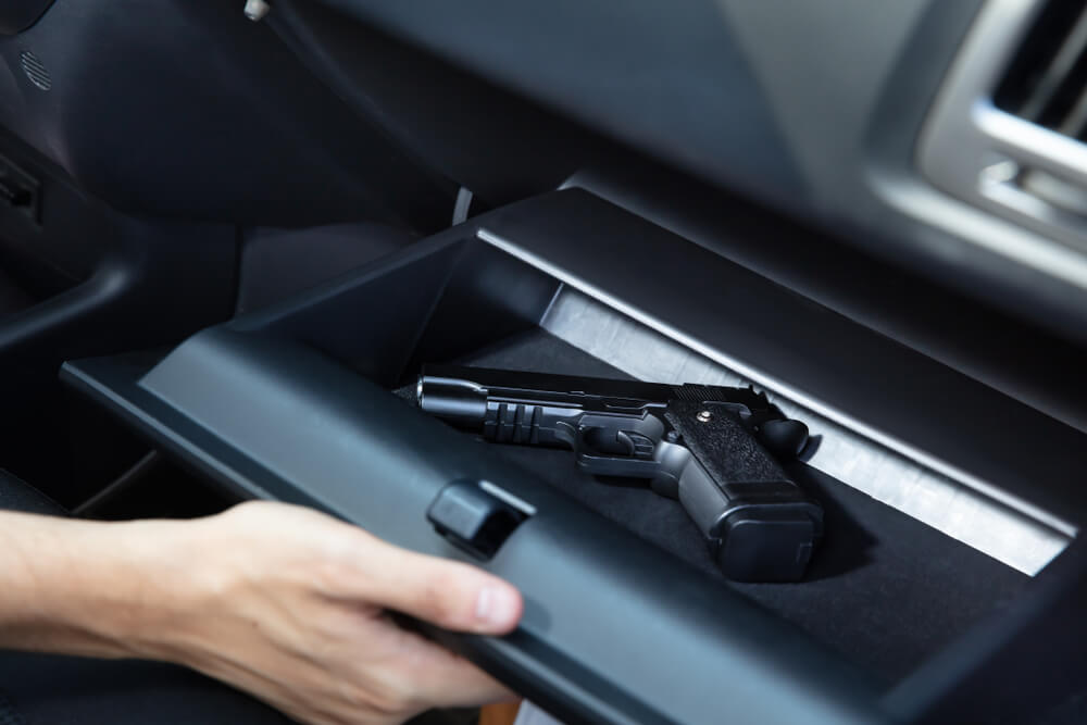 Handgun resting inside an open car glove compartment.