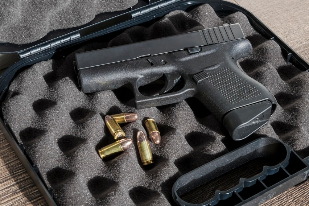Handgun and ammunition inside an open protective carrying case.